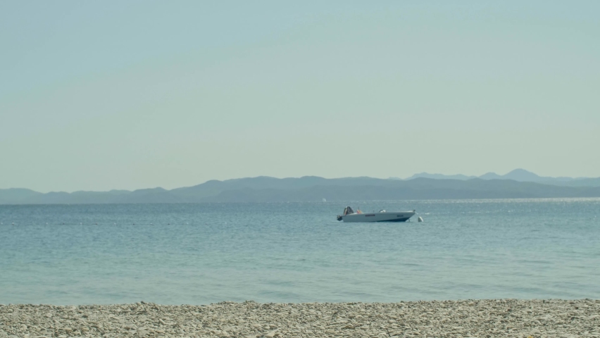 A young man in a suit, wearing a tie and doing various jumps while running on the sea beach at sunset. He does somersaults and poses for the camera.