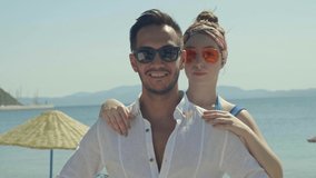 Blowing air kiss of young couple at seaside. Slow motion 4k video. Young couple smiling for the camera on a sunny summer day. An adventurous journey to the wonderful sea view.Slow motion video.