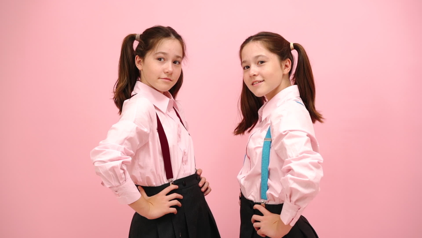 Beautiful little twin schoolgirls with twin tails shaking heads from side to side. Over pink background studio shot. | Shutterstock HD Video #1062055993