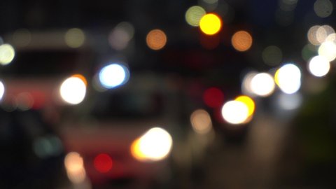 Beautiful glittering bokeh in dark blurry background at night. The round colorful bokeh shine from car lights in traffic jam on city street. It reflect lonely capital city lifestyle. Abstract concept.