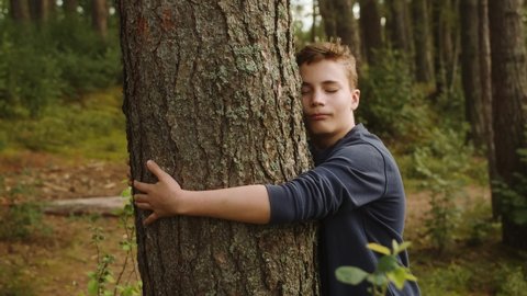 Boy hugs around a tree showing his love to nature.