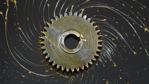 Super Slow Motion Shot of Rotating and Splashing Metal Cogwheel on Dark Background at 1000 fps.
