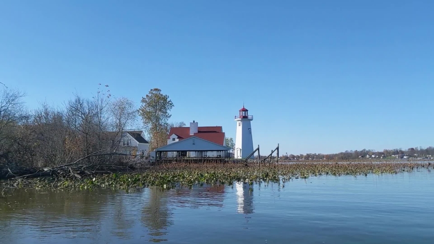 White lighthouse on lake, blue sky, reflection - dolly shot