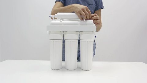 Male hands dismantling small parts from reverse osmosis water filter
