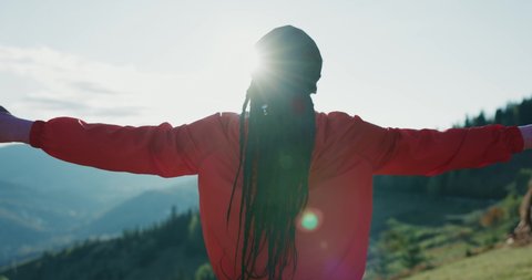 Inspired young meditating african american woman spreading arms breathing fresh air enjoying morning workout outdoor training in cinematic mountains. Zen, wellness, peace concept.