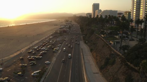 Famous Bridge overpass over Pacific Coast Highway by Santa Monica Beach in Los Angeles with light traffic in beautiful golden hour Sunset vibe, Aerial Dolly forward, Wide angle shot