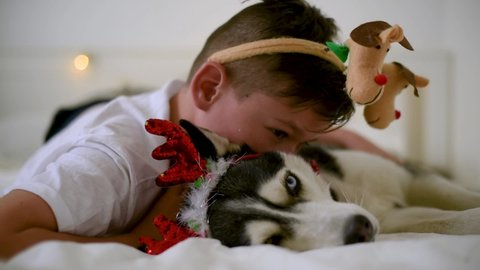 Handsome boy with carnival horn kissing the funny husky dog