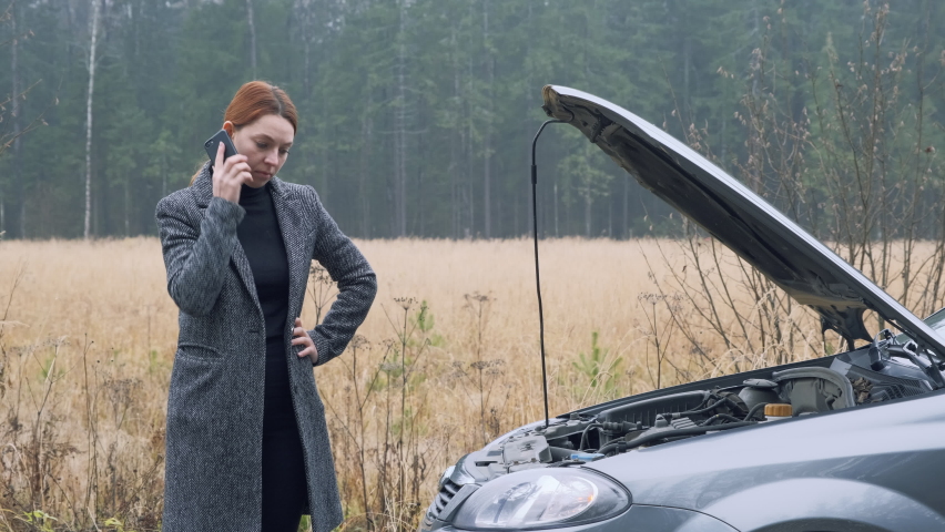 Young business woman on countryside road trying to get help with her broken down car and call evacuation