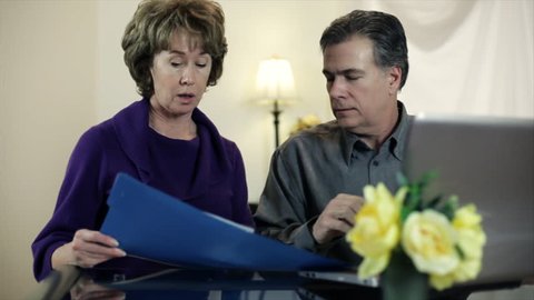 A mature couple working on some paperwork using their wireless laptop computer.