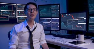 Asian business man is analyzing online stock market trading graph, crypto growth chart with monitors showing on screen. Alone male video conference of financial strategy at late night. Web cam view.