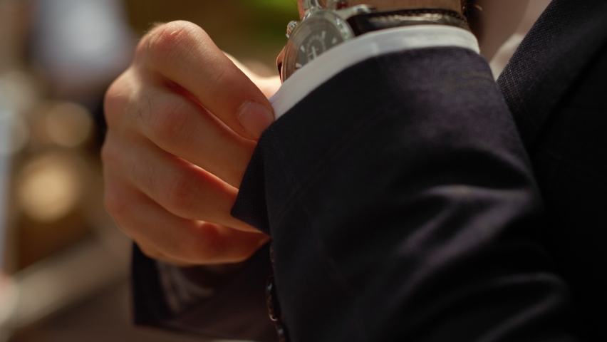 Closeup man hands with wrist watch in park. Male person in formal wear getting better sleeves outdoors. Unrecognizable rich man buttoning up shirt sleeve under arch in garden. | Shutterstock HD Video #1062090178