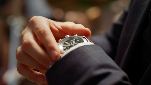 Closeup unrecognizable man looking at wrist watch in park. Male person in formal suit checking time outdoors. Unknown man getting better sleeve in garden. Guy hiding watch under sleeve