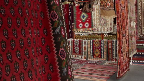 Yerevan / Armenia - 08 13 2019: Hanging colourful rugs in market with adult male walking through In Yerevan, Armenia 