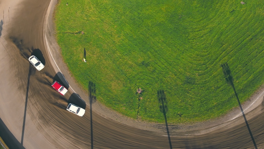 Aerial view on top Races on the racetrack. Cars driving in a circle drifting around corners compete for first place in car racing.
