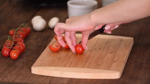 Female Hands Cut Cherry Tomatoes On Halved With a Knife.