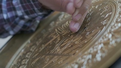Bukhara master engraves patterns on a tray. Close up, slow motion