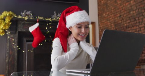 Caucasian woman at home at Christmas, wearing Santa hat, making video call on laptop, smiling and blowing a kiss, slow motion. Social distancing during Covid 19 Coronavirus quarantine lockdown. ஸ்டாக் வீடியோ