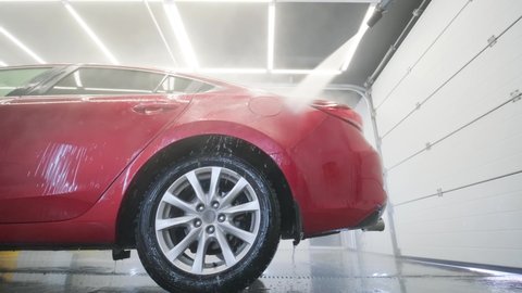 KYIV, UKRAINE - August 2020: Car washing cleaning with foam and high pressured water. Red car