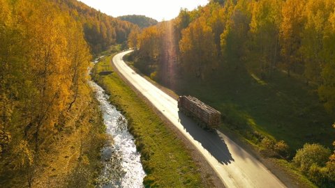 Incredible mountain road with a timber truck. Wonderful autumn colors.