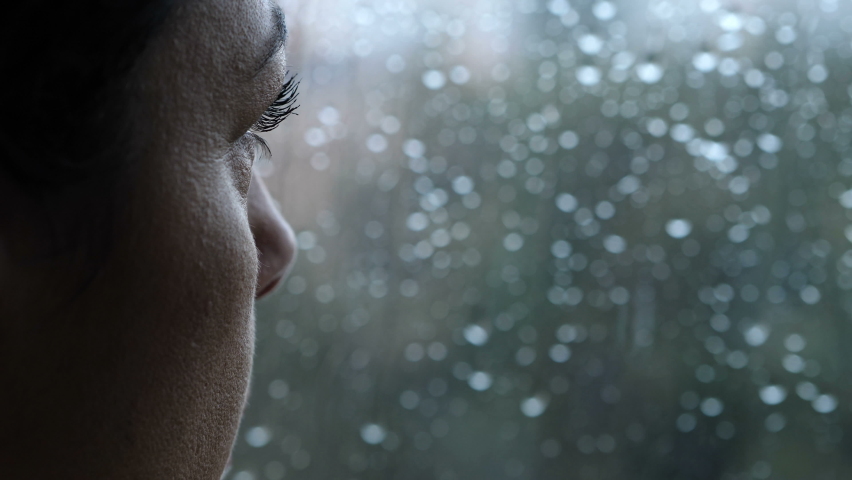 Sadness, depression - pensive woman looks out the window in a rainy day - macro