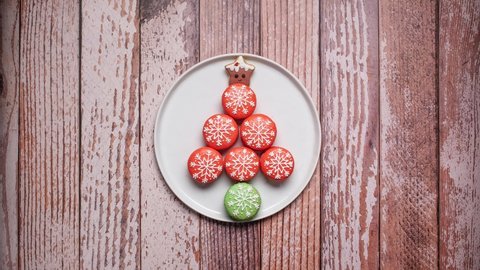 Christmas macarons in the shape of a Christmas tree with gingerbread star tree topper disassembling with all macarons leaving.  4K stop motion animation video