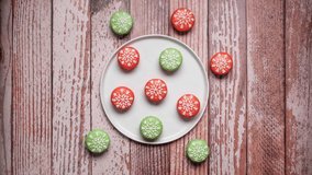 Christmas macarons on a plate with the middle one having bites taken out of it.  4K stop motion animation video