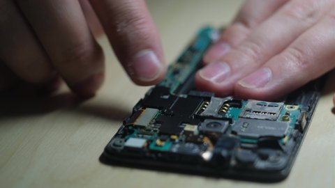 Master repairs a smartphone in a service center, closeup