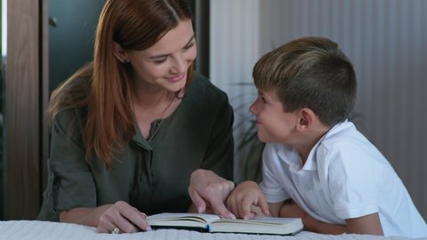 Christian family, believing mom and son enjoy reading the Bible at bedtime in room, religion and faith