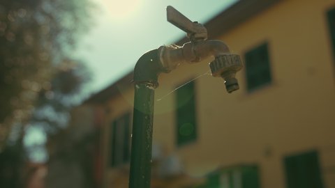 cinematic dolly shoot of an outdoor tap slow water dripping. Leaking tap water. Help save water. shot in slow motion