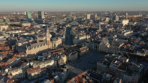 France, North, Lille, right to left drone aerial view above the Général De Gaulle Grand-Place during sunset (or sunrise), belfry of the chamber of commerce and train station in the background