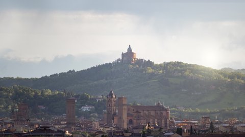 Time lapse of aerial view of old medieval town Bologna with Santuario della Madonna di San Luca with portici in background, during a sunny cloudy day. There is the Cathedral with asinelli tower
