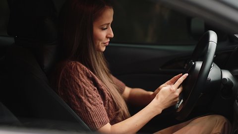 transport, vehicle and technology concept - smiling woman in car using smartphone. corresponding with colleagues using a smartphone. Internet and technology concept. 4k