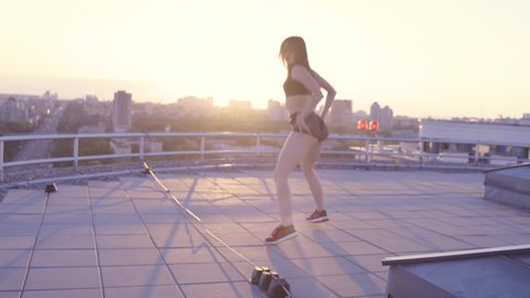 Brunette woman moving hips and butt, dancing twerk on the roof top, flirting