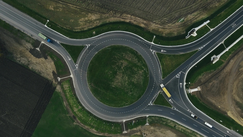 Roundabout traffic of cars and trucks on the circle ring road aerial top view Royalty-Free Stock Footage #1062128071