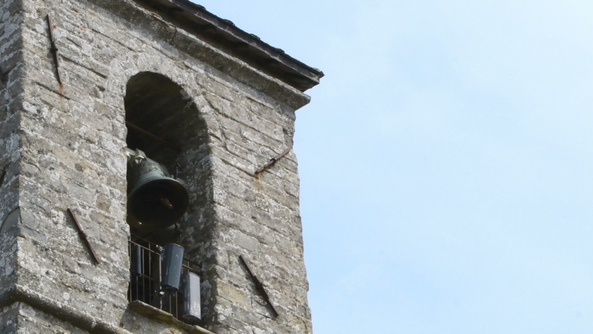 Close up of a dark bell of a bell tower with exposed bricks as it swings and rings - Sanctuary of the Verna medieval village near Arezzo – Real Time 4K
 | Shutterstock HD Video #1062128479