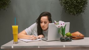 4k wide video of young Latin Hispanic woman working on modern laptop in garden cafe or home garden patio.