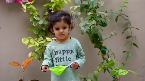 nov 2020,sirsa,haryana
Portrait of a funny Cute Indian kid baby girl try to  wearing a mask on her face to protect herself from dangerous coronavirus  and behind is beautiful plants and green leaf, 