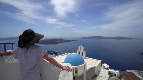 Carefree woman tourist in European destination wearing hat enjoy view of Santorini panorama over Virgin Mary church, Three Bels of Fira
