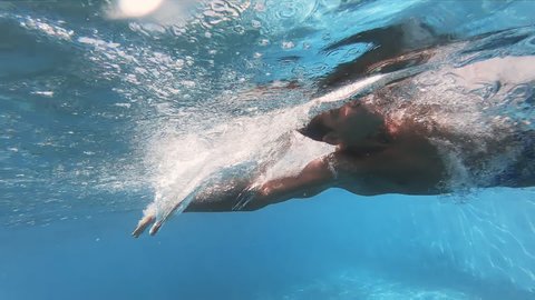 Young swimmer man swimming crawl in an olympic pool, slow motion