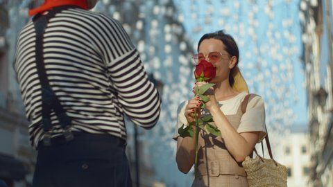 Mime giving a red rose to a young girl in the city