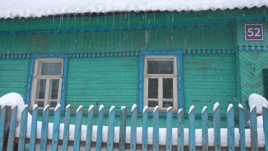 Traditional wooden house at hard snowfall.