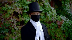 Handsome Young Man Wearing A Frock-Coat And A Top Hat Taking Off His Face Mask