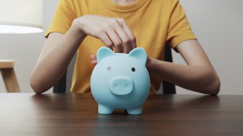 Young woman put coins in a piggy bank with saving money is investment for the future. Calculate income and expenses in daily life.
