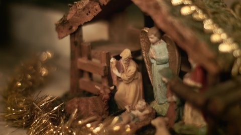 Woman puts miniature figurines of Mary and Joseph in a christmas crib. Beautiful nativity scene and christmas decorations - close view