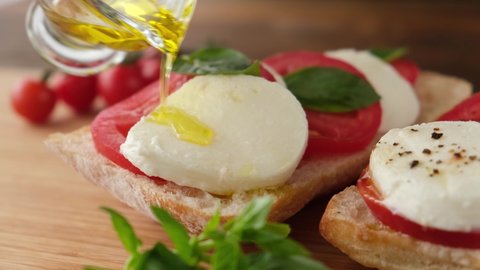 Italian panini with mozzarella cheese, tomatoes and olive oil. Closeup view. Pouring olvie oil on caprese sandwich