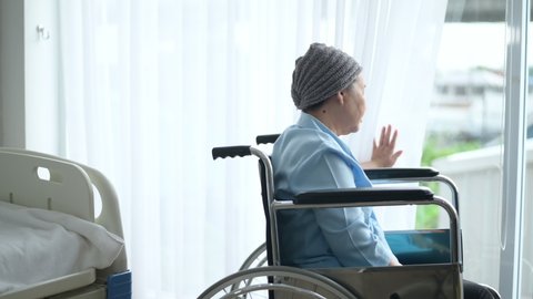 Depressed and hopeless Asian cancer patient woman wearing head scarf in hospital.	

