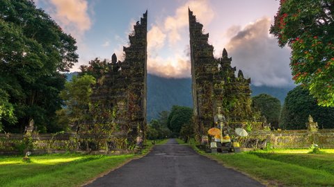 Beautiful traditional hindu Gate at sunrise on background scenery mountain in fog. Bali is a famous destination for its breathtaking nature and culture. 4K
