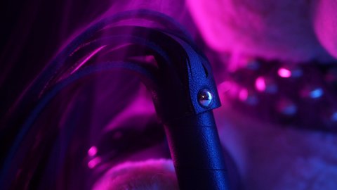 toy bear dressed in leather belt harness accessory for BDSM games on a dark background in neon light in the smoke