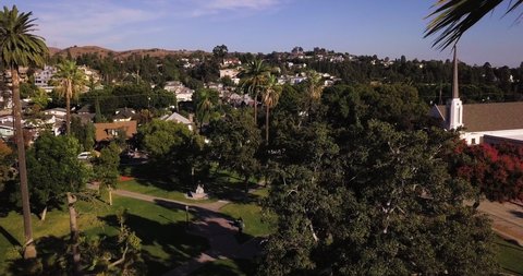 Whittier , California / United States - 10 19 2019: beautiful palms and green field, Central Park Historic District with First United Methodist Church on the right. Aerial drone establishing shot