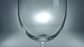 Creative macro slow motion raw video of white wine pouring into a glass. Glass with pouring white wine close-up with splash and bubbles.